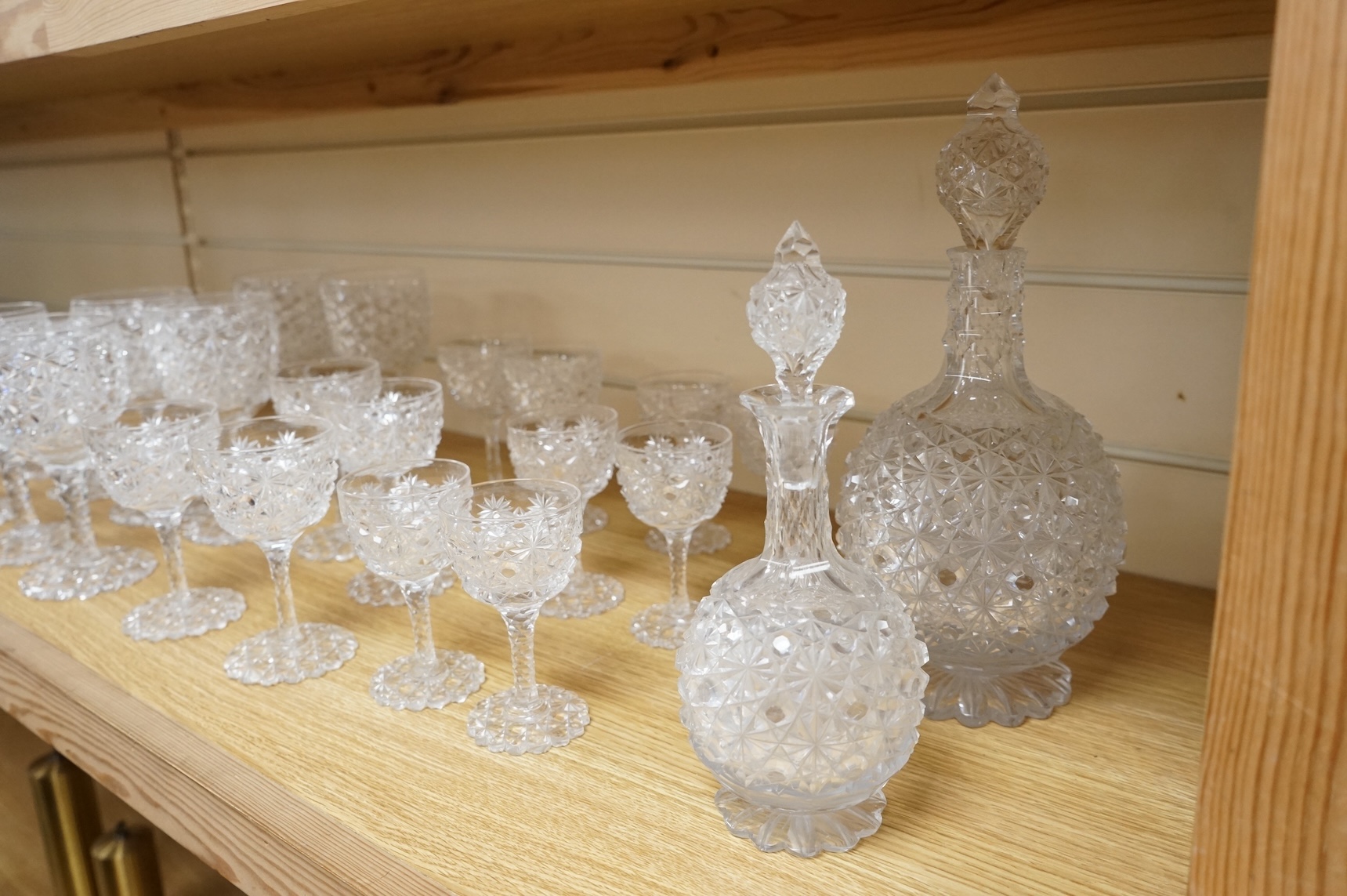 A Victorian heavy hobnail and star cut suite of table glass to include champagnes glasses and two decanters, largest 29cm high